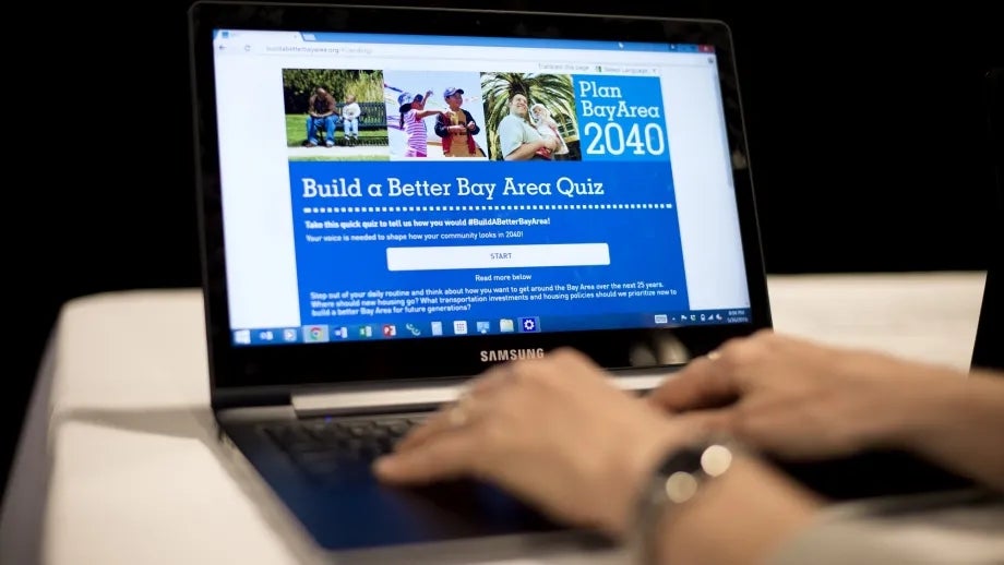 A computer user has her hands on a laptop's keyboard, as the screen displays the Build A Better Bay Area website homepage.