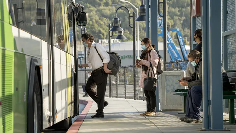 Adults boarding a bus on their workday commute.