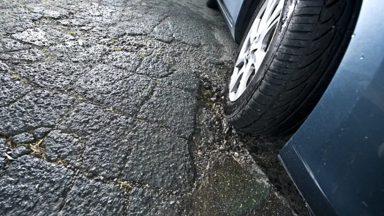 A car’s tire driving through a pothole