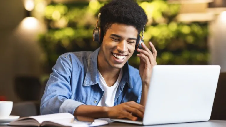 Young man smiling at laptop with headphones