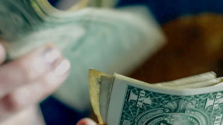 Closeup of a person counting one-dollar bills.