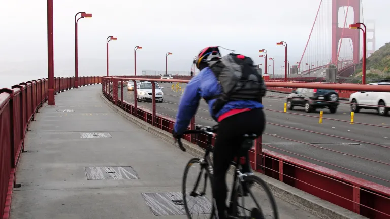 A cyclist on the Golden Gate Bridge path on a foggy morning.