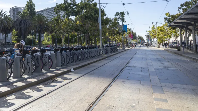 A public bikeshare dock next to a train/bus stop in San Francisco.