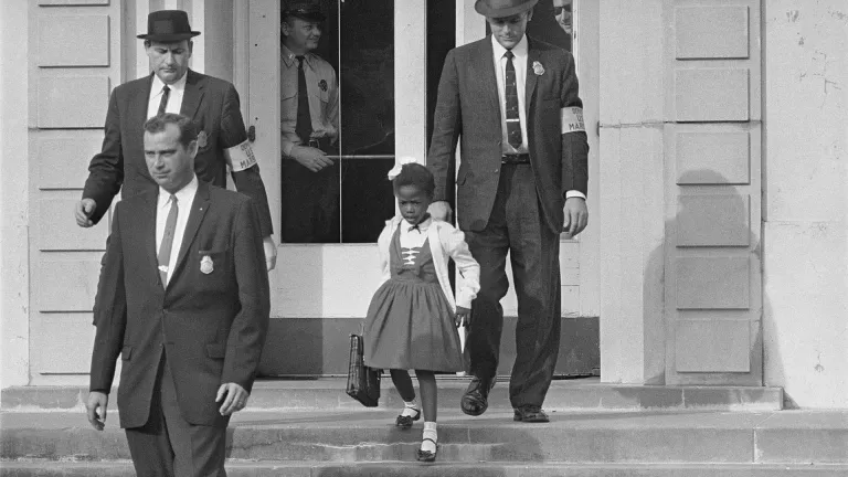 Ruby Bridges as a child on the school steps, being escorted by officials.