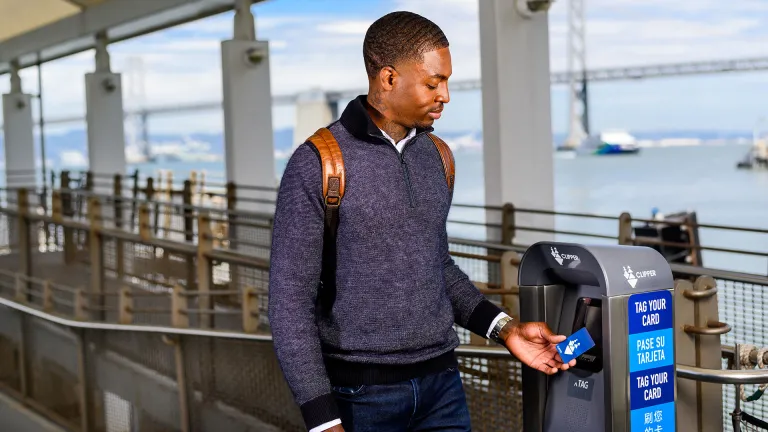 A person tagging his clipper card before boarding a ferry.