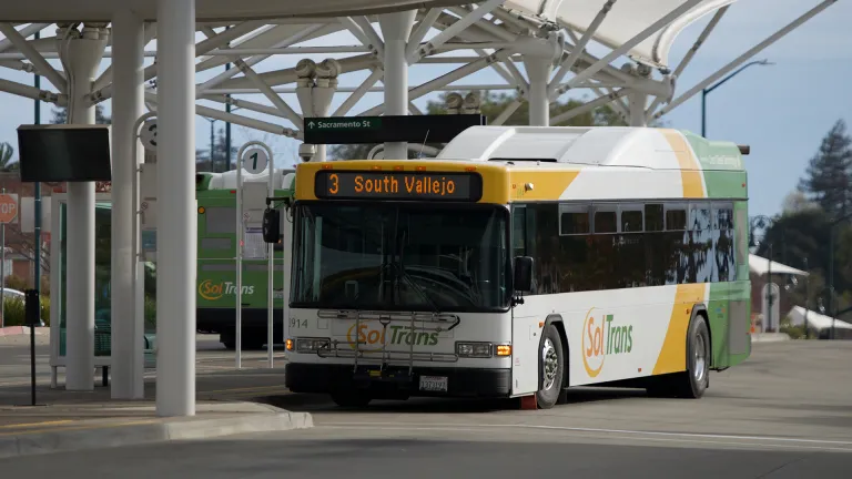 A SolTrans bus sits at a bus stop at the Vallejo Transit Center on a sunny day.
