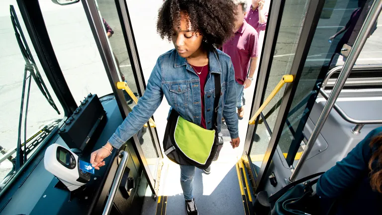 A young person tags their clipper card while boarding a bus.