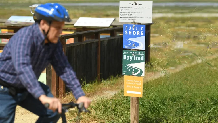 A cyclist rides past a Bay Trail sign.