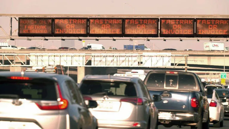 Heavy traffic beneath an electronic toll plaza sign indicating FasTrak or Invoice.