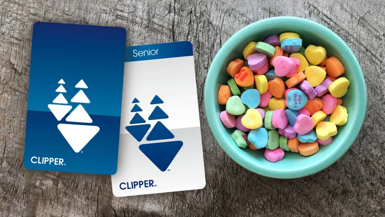 A Clipper card and a Senior Clipper card next to a bowl of Valentine's Day candy hearts.