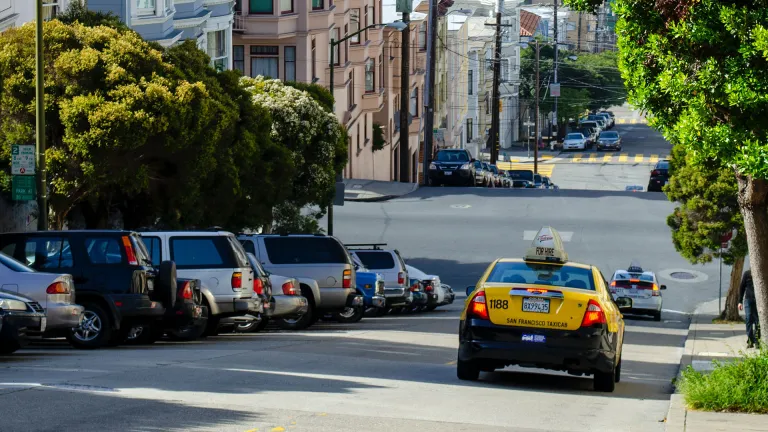 A yellow taxi on a hilly street in San Francisco.