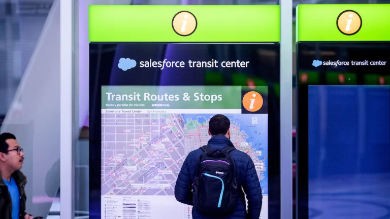 A person stands in front of the "Transit Routes and Stops" map at the Salesforce Transit Center.
