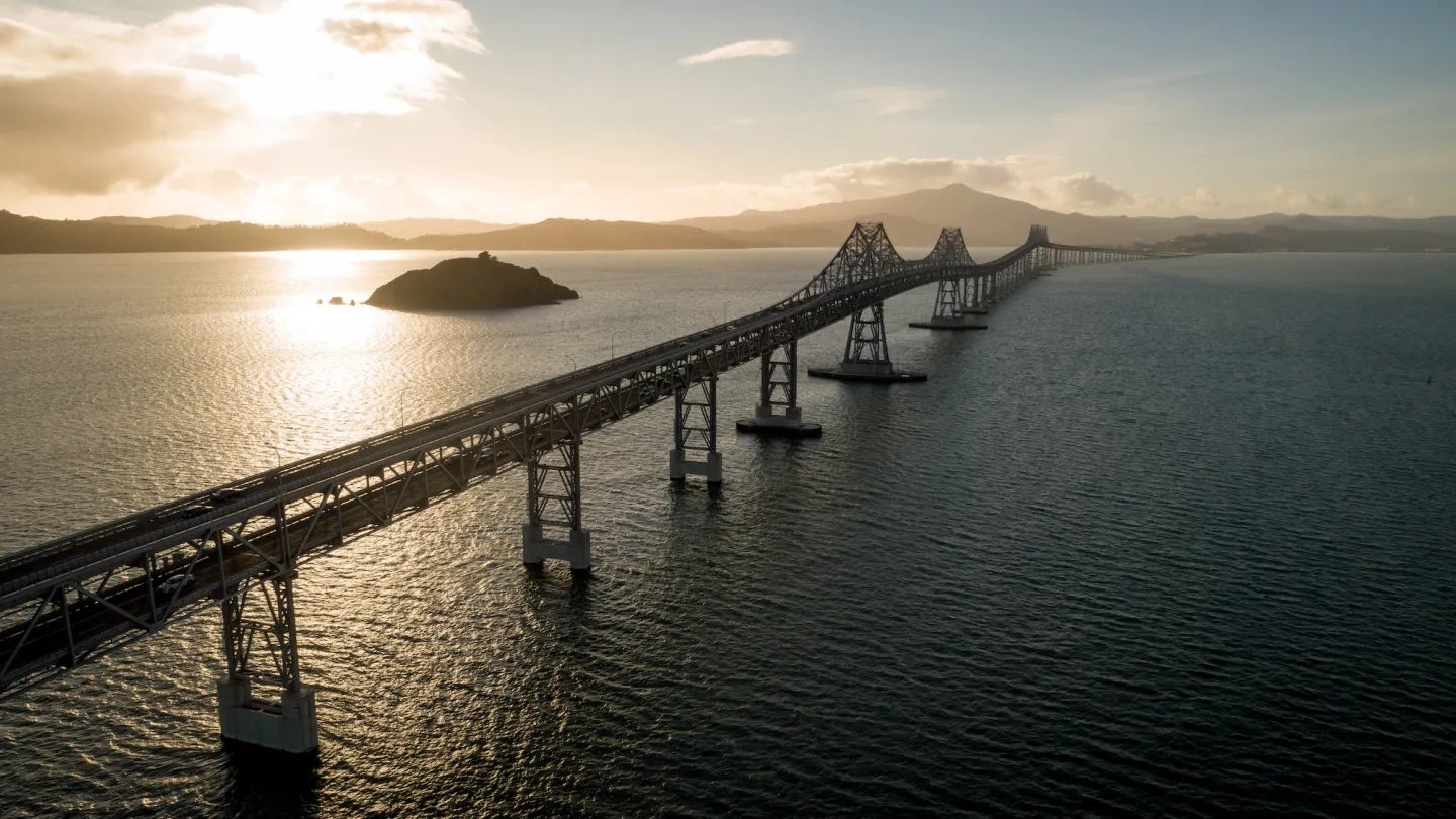 The sun rises in the background in this aerial view of the Richmond-San Rafael Bridge