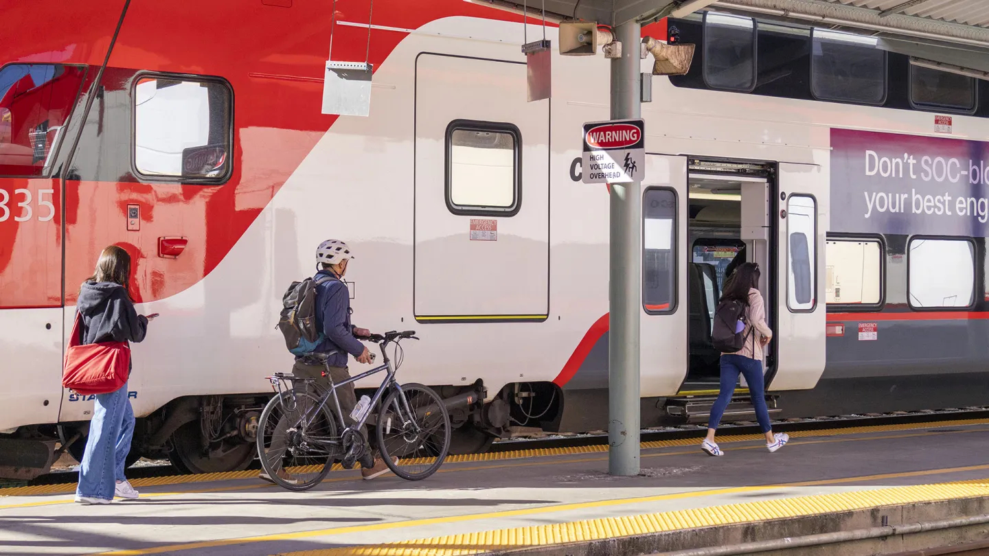 A person walks their bicycle to the bike car at Caltrain.