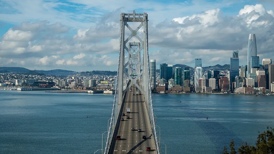 Light traffic on the San Francisco-Oakland Bay Bridge, with the San Francisco skyline beneath beautiful blue skies. 