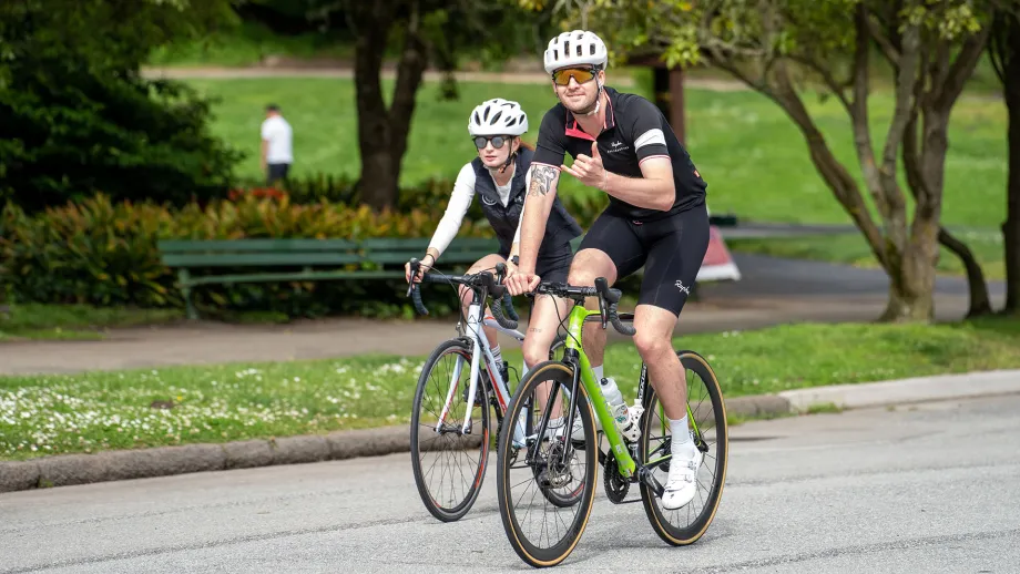 Two athletic cyclists in Golden Gate Park. One gives the Shaka sign with his left hand.
