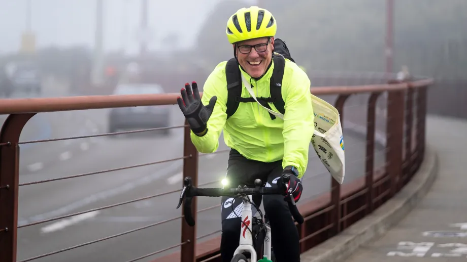 A cyclist in a neon jacket and helmet rides across the Golden Gate Bridge on Bike to Work Day.