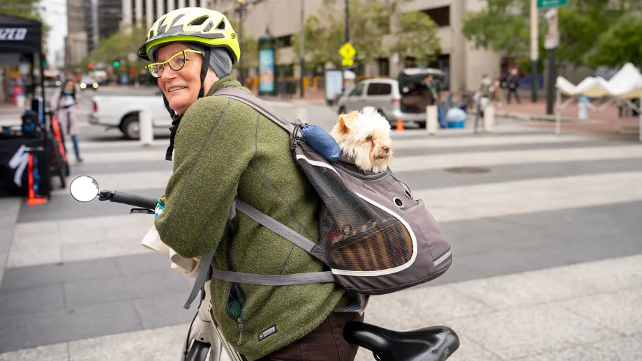 A person on a bike with a small dog in a backpack.