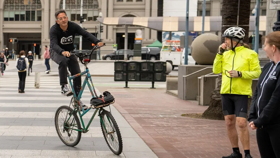 A person rides a custom double-decker bicycle in the plaza in front of the San Francisco Ferry Building.