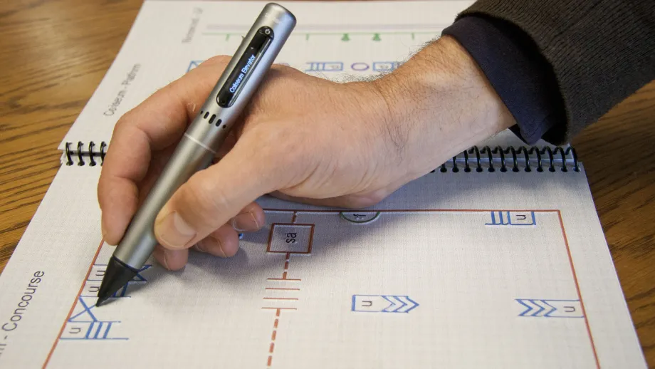 A hand holds a specially designed pen to "read' a tactile map