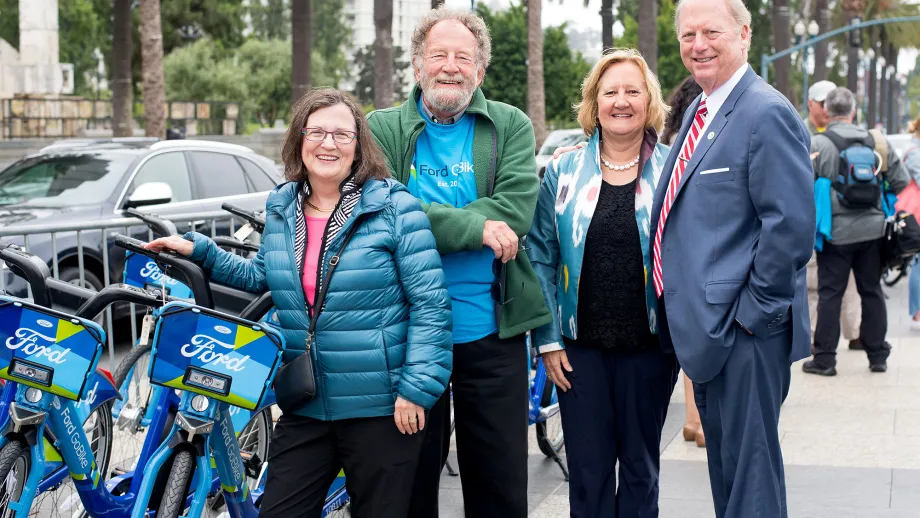 4 people posing for a picture with a go bike