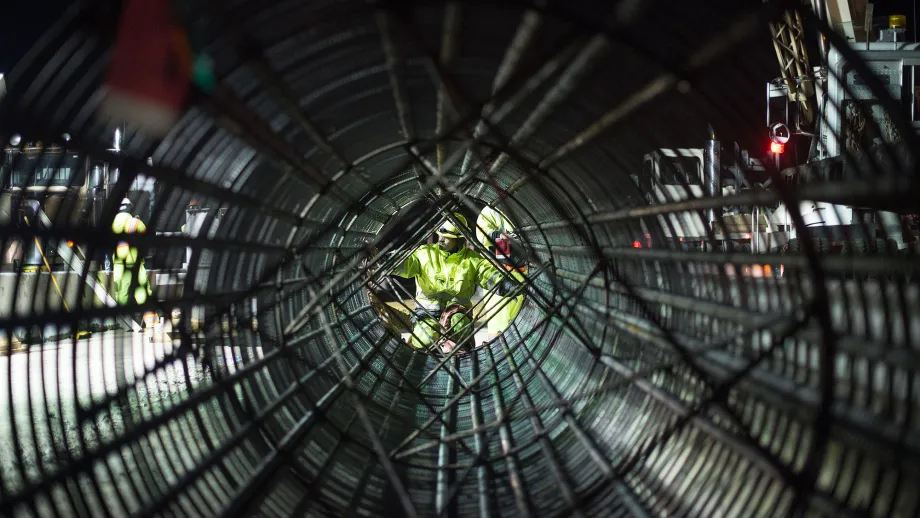 A view through a pre-fabricated rebar cage as crews prepare to lift it with a crane.