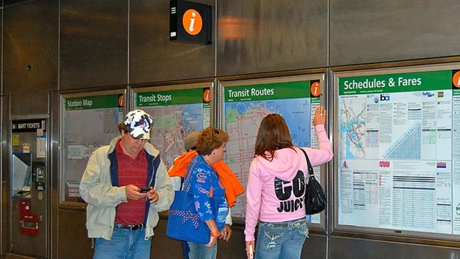Transit riders read maps and information in the BART/Muni station.