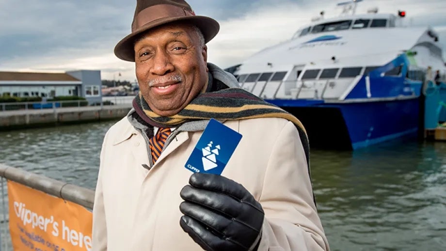 Senior holding Clipper card at ferry dockside.