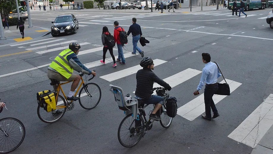 Cyclists, pedestrians and vehicles at an intersection.