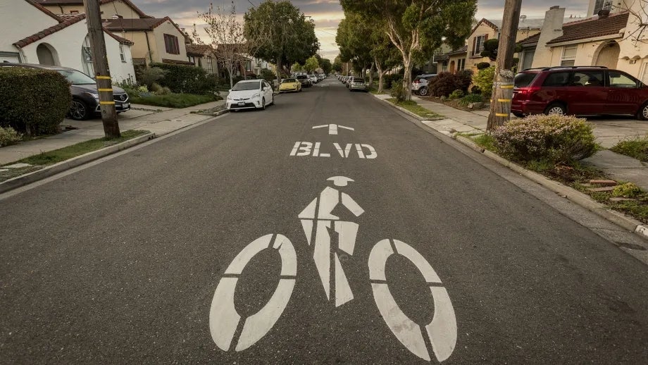 A "bicycle boulevard" symbol painted in the middle of a suburban street.