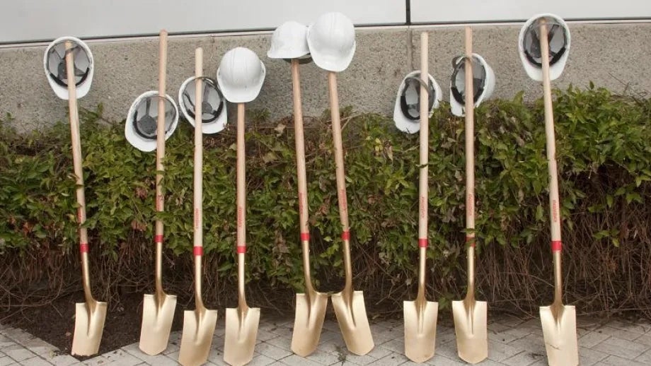 Mementos of a recent groundbreaking project: several gold-painted shovels with hard hats hanging on the handles.