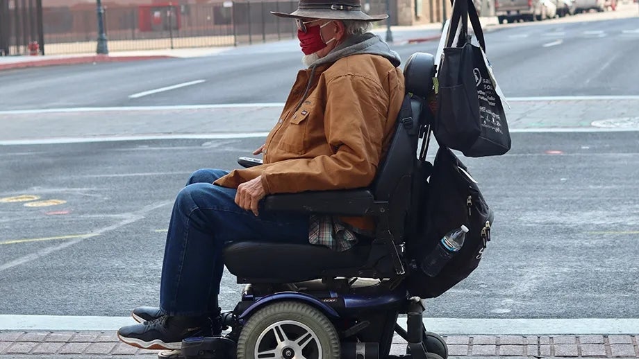 A person in a motorized wheelchair crossing the street.