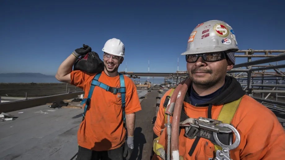 Two happy construction workers on a job site for an MTC-funded project.