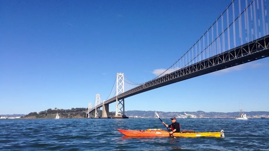 A kayaker paddles on the San Francisco Bay Water Trail, beneath the San Francisco-Oakland Bay Bridge.