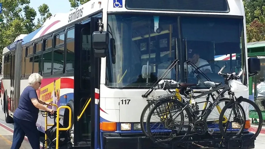 A senior with a walker boarding a SamTrans bus by using the vehicle lift.