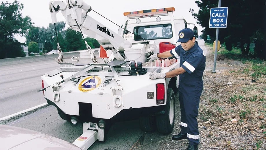 Freeway Service Patrol technician using a tow truck to assist a freeway motorist.