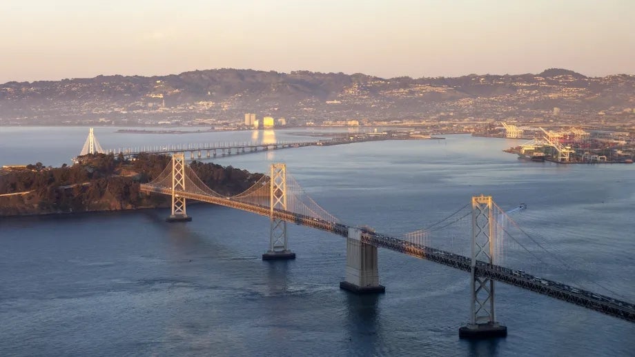 The San Francisco-Oakland Bay Bridge at sunset with the Berkeley/Oakland hills beyond the Bay.