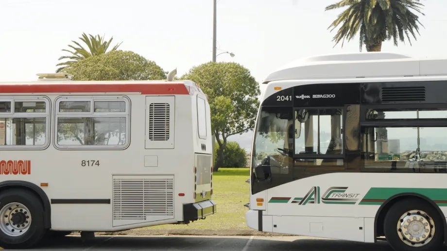 A Muni bus and an AC Transit bus parked next to each other.