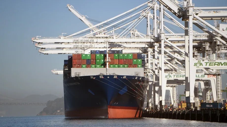 A cargo ship loaded with shipping containers docked at the Port of Oakland.