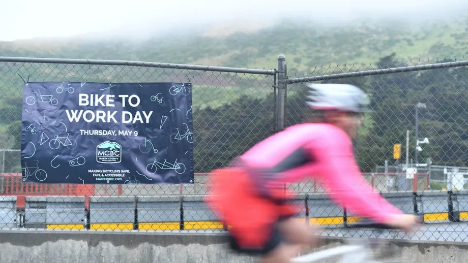 A cyclist rides past a Bike to Work Day banner
