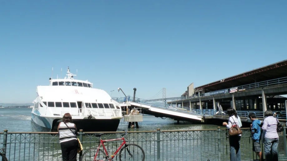 A cyclist looks out at a ferry boat at the San Francisco Ferry Terminal.