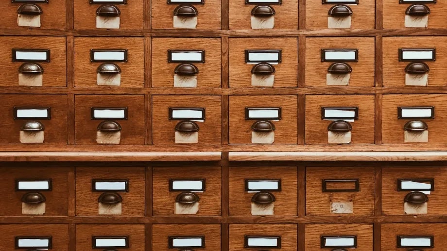 An old card catalog with wooden drawers and individual labels.