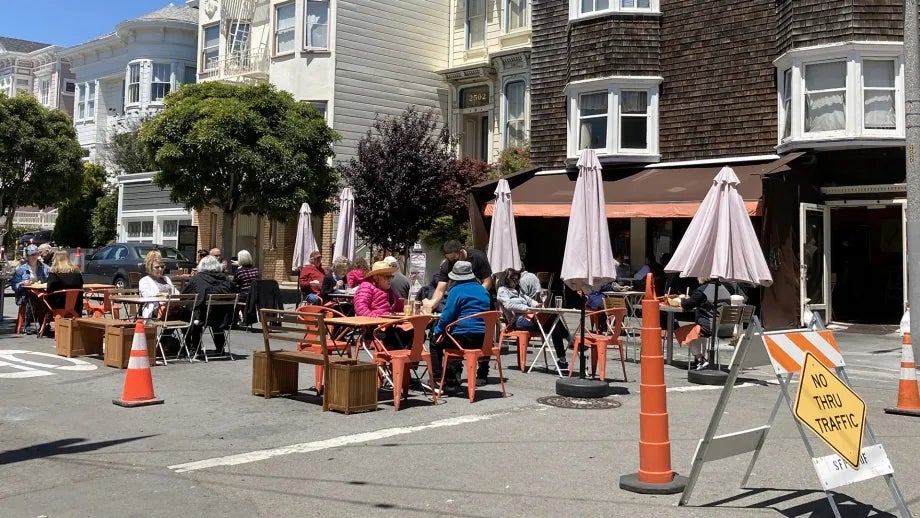 Restaurant customers dine outside on a San Francisco street that is closed to cars.