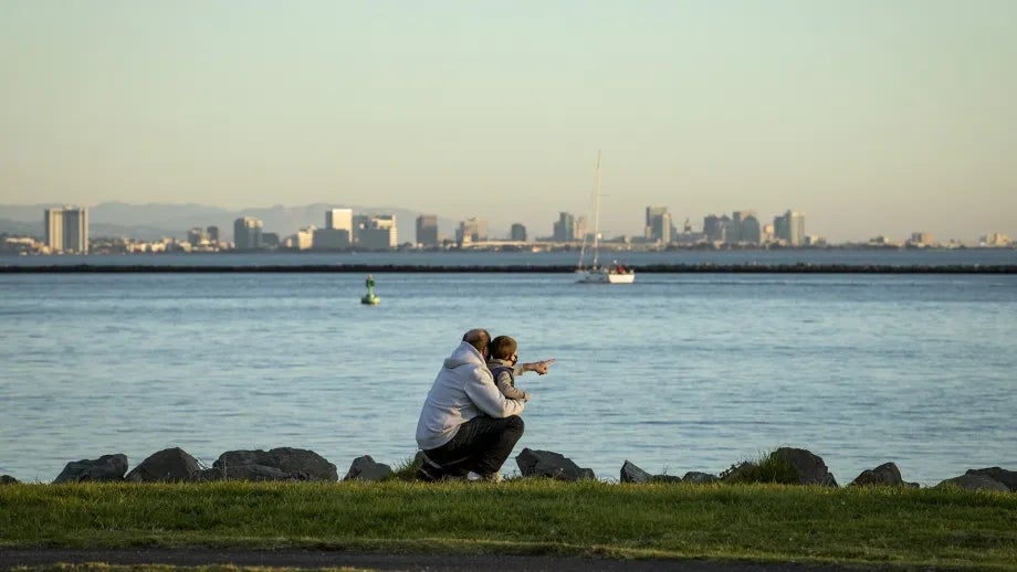 An adult and child pointing at the water in Richmond, California.
