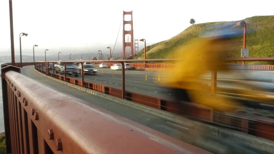 The bicycle/pedestrian path on the Golden Gate Bridge, with a blurred cyclist whizzing past.