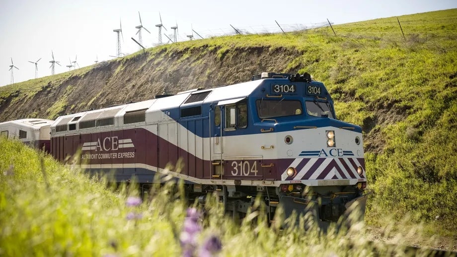 An Altamont Corridor Express (ACE) train travels through rolling hills.