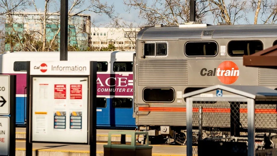 A Caltrain and an ACE train pass each other at a station.