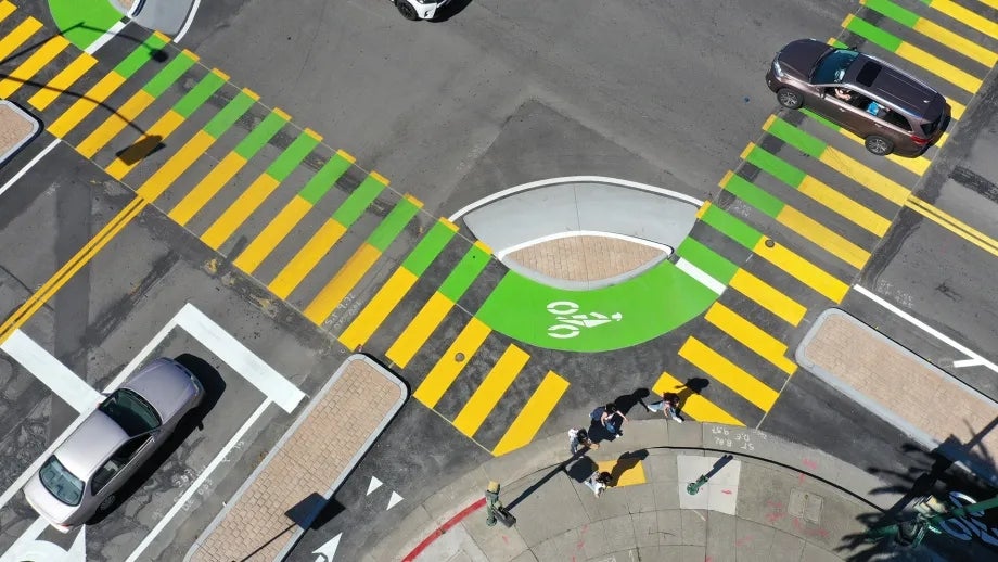 Aerial view of an intersection with boldly-painted crosswalk stripes and bicycle lanes.