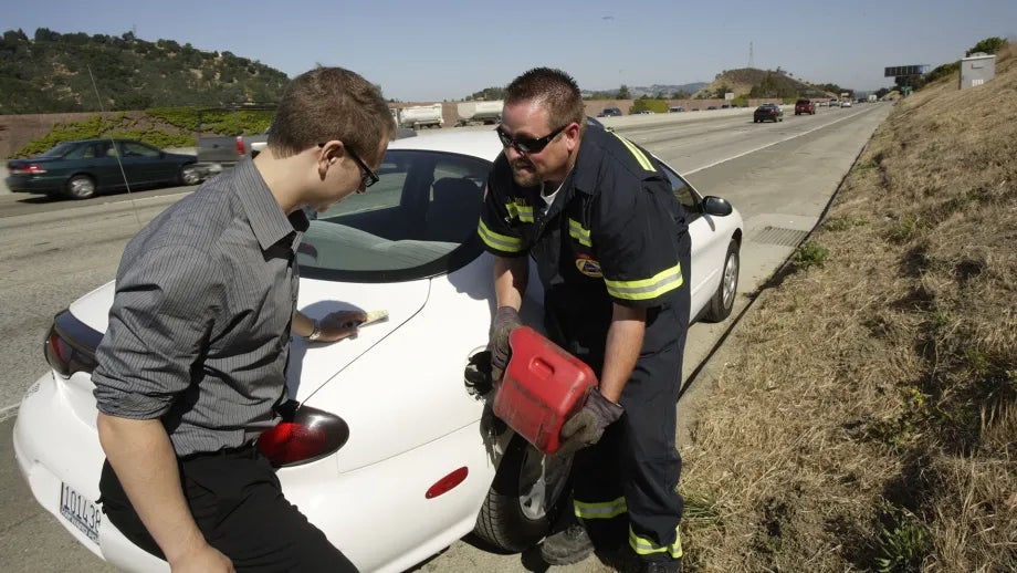 A Freeway Service Patrol technician provides gas to a stranded motorist.