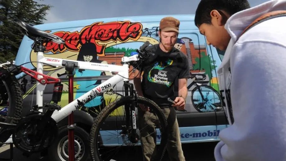 A BikeMobile team member helps a boy fix his bike.
